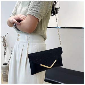 Detail of black glitter evening bag with gold V-metal trim and elegant chain strap