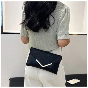 Detail of elegant black sequin clutch with gold V-metal trim and chain strap