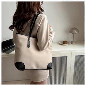 Detail view of a large canvas tote bag with black leather trim and gold rivet accents