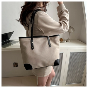 Detail of canvas tote bag showing contrast leather trim and sturdy handle on shoulder