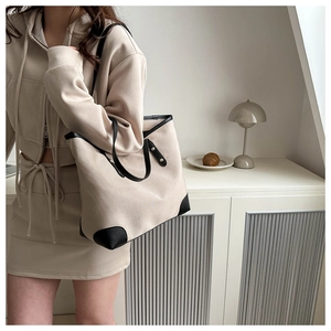 Close-up of canvas tote bag featuring black leather trim and reinforced bottom corners
