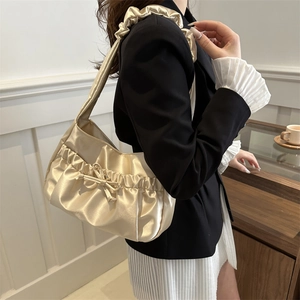 Elegant champagne satin hobo bag with bow decoration and pleated strap on a model