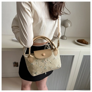 Detail of floral embroidery on a beige woven handbag with brown faux leather handles