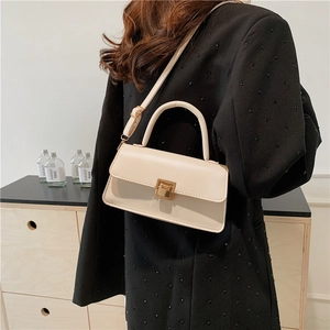 Cream white crossbody bag with gold buckle lock on black suit blazer model