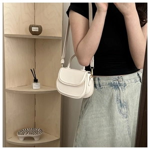 Detailed close-up of a white retro saddle bag with gold hardware and shoulder strap
