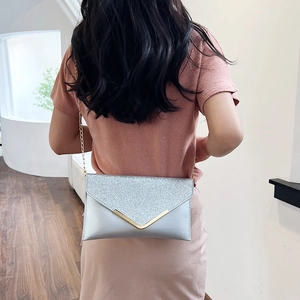 Elegant silver glitter evening clutch with gold V-trim and delicate chain strap on model