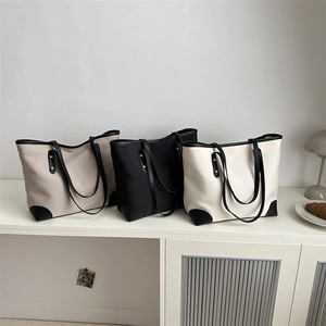 Three minimalist canvas tote bags with leather trim displayed in a clean lifestyle setting