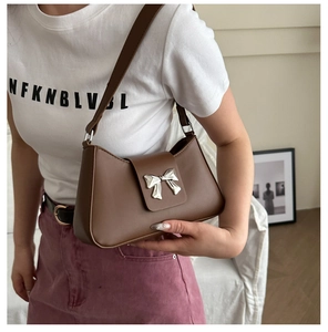 Detail of a brown PU leather shoulder bag featuring a silver metal bow buckle design