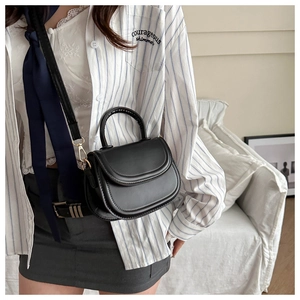 Close-up of black saddle bag with gold metal hardware and adjustable shoulder strap