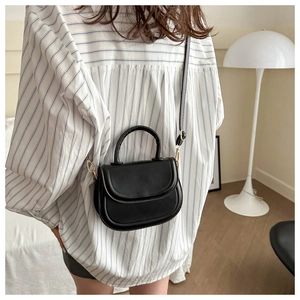 Detail view of a black retro saddle bag featuring golden hardware and top handle strap