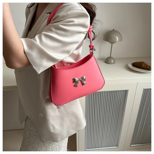 Detail of bright pink underarm bag featuring a metallic silver bow clasp and PU leather