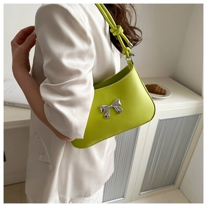 Detail of bright green PU leather shoulder bag with silver metal bow and knot strap