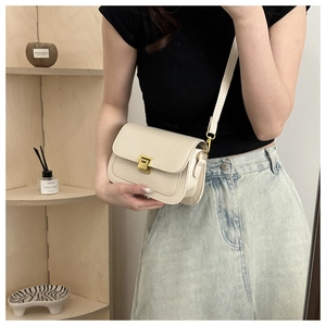 Detail of minimalist beige crossbody bag with golden clasp shown in a lifestyle mirror shot