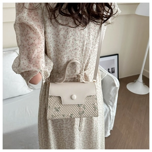 Detail of woven straw handbag with floral embroidery and cream leather finish