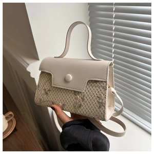 Detail of floral embroidery on beige crossbody bag with premium leather handle