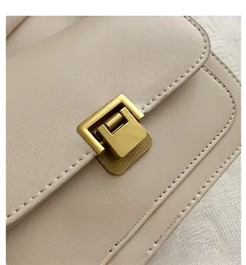 Macro detail of creamy saddle bag showing fine leather grain and vintage brass buckle
