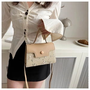 Detail of beige straw crossbody bag featuring floral embroidery and leather flap