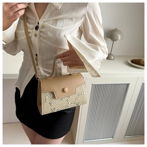 Stro handtas met bloemenborduurwerk en lederen details getoond op een model