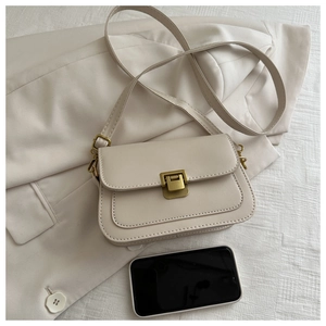 Detail of beige PU leather crossbody bag with vintage gold metal push-lock on a blazer