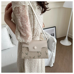 Detail van geweven beige handtas met bloempatronen en decoratieve ronde knoop
