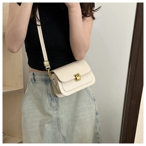 Detail of cream white leather crossbody bag with vintage gold metal lock and fine stitching
