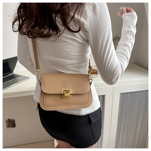 Detail of light brown retro crossbody bag with golden square lock worn by a model