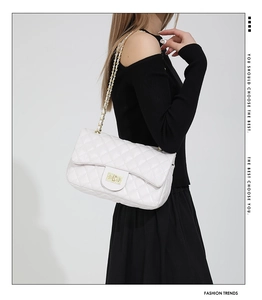 Detail of white quilted leather chain bag featuring gold metal twist-lock and woven strap