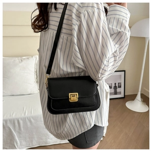 Detail of minimalist black crossbody bag with gold twist lock and matte leather finish