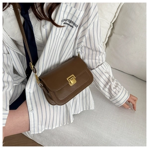 Detail view of a vintage dark brown leather crossbody bag with a gold metal push lock buckle