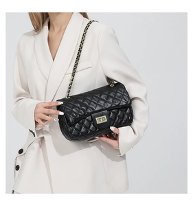 Detail of black quilted shoulder bag featuring gold twist lock and metal chain strap