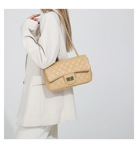 Close-up of beige quilted shoulder bag with gold metal twist lock and chain strap detail