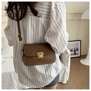 Close-up of a brown vintage leather crossbody bag with a gold rectangular metal lock