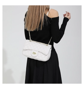 Close-up of a white quilted crossbody bag with a gold chain strap and metal turn-lock