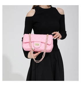 Detailed close-up of pink quilted crossbody bag with gold-tone hardware and metal chain strap