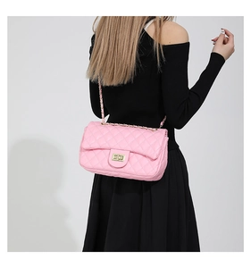 Detail of pink quilted leather crossbody bag with gold chain strap on a model