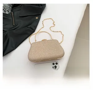 Detail of champagne gold evening clutch with glitter texture and pearl clasp fitting a phone