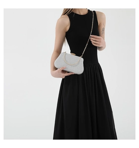 Detail of silver sequin evening bag with gold handle and chain on black dress