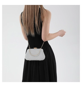 Silver glittering evening clutch bag with gold chain strap shown on model shoulder
