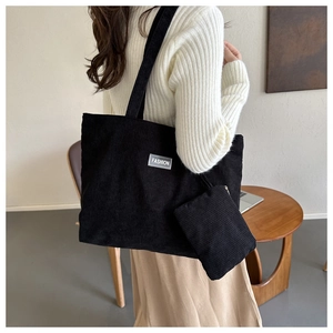 Detail of black corduroy tote bag set with silver Fashion label and small purse