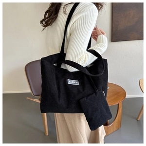 Detailed texture of black corduroy tote bag with small matching pouch and fashion label