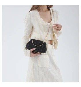 Detail of black glitter evening clutch with gold metal handle and fine chain strap