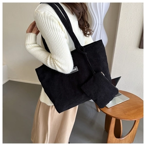 Detail of black corduroy tote bag with fashion patch and matching small zipper pouch