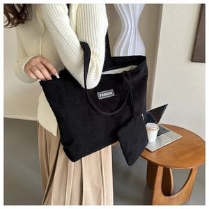 Detail of black corduroy tote bag with striped texture and small matching pouch charm