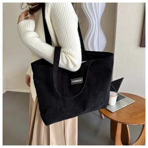 Detailed texture of black corduroy tote bag featuring a Fashion label on the front
