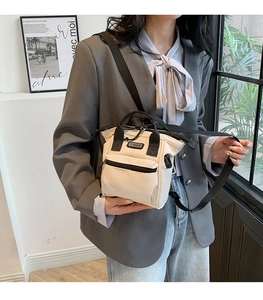 Détail du sac bandoulière en toile crème avec logo sport et bandoulières noires