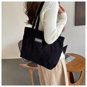 Close-up of black corduroy tote bag featuring a Fashion label for casual daily commute