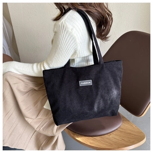 Detailed texture of black corduroy tote bag with fashion label and large capacity