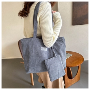 Detail of grey-blue corduroy tote bag with small pouch and fashion label on shoulder
