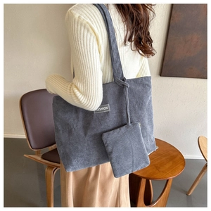 Gray corduroy tote bag detail showing striped texture, fashion label and small zipper pouch