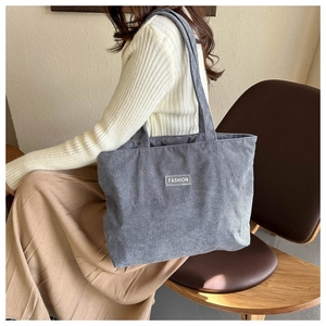 Detail of grey corduroy tote bag showing striped texture and Fashion label patch
